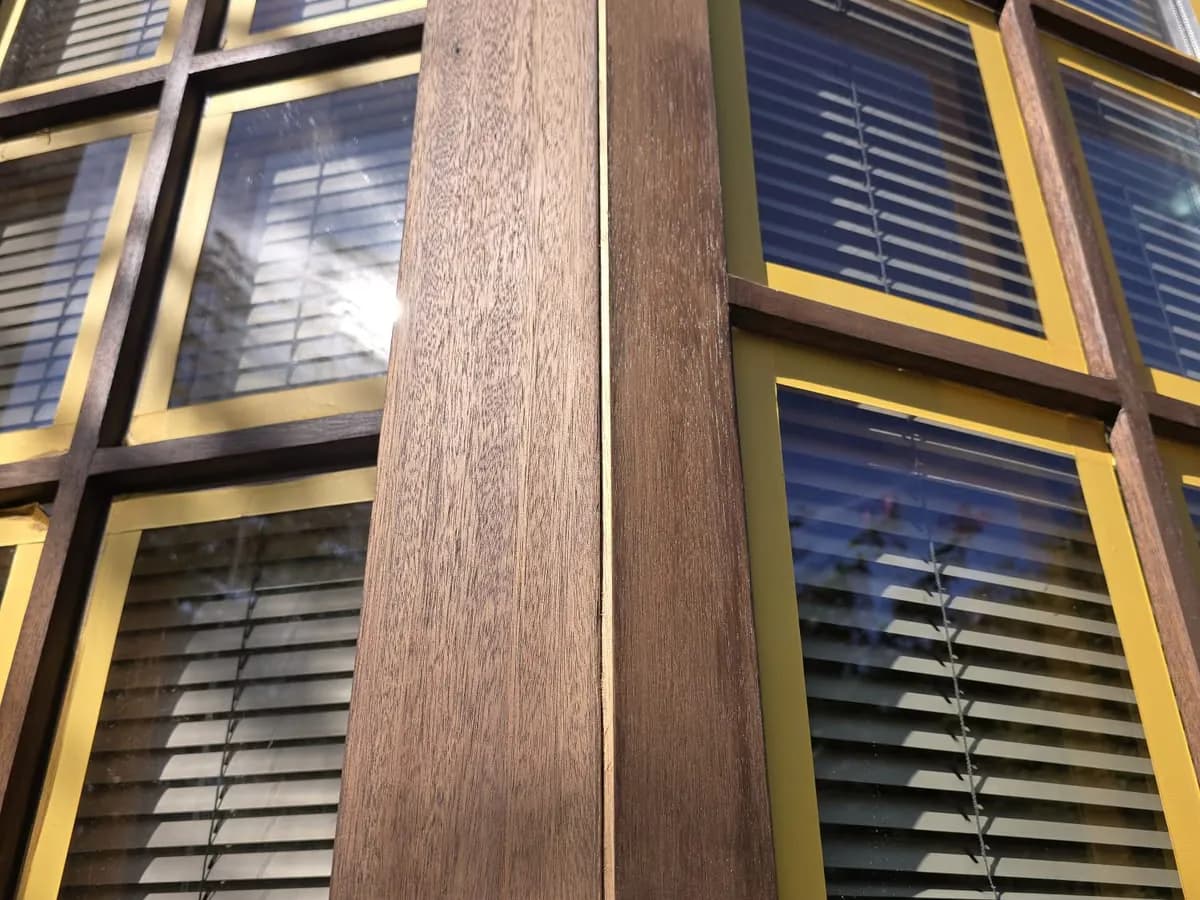 Holzfenster geschliffen: Eckpfosten eines Erkers bis aufs rohe Holz abgeschliffen, die Glasscheiben mit gelbem Klebeband abgeklebt