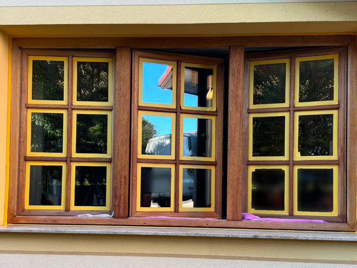 Holzfenster vorbereitet: dreiteiliges Sprossenfenster mit geschliffenem Rahmen, jede Glasscheibe mit gelbem Klebeband abgeklebt