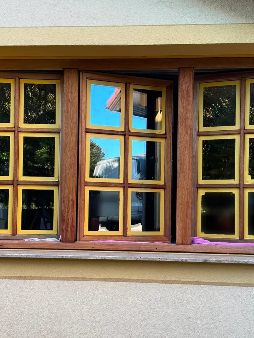 Holzfenster vorbereitet: dreiteiliges Sprossenfenster mit geschliffenem Rahmen, jede Glasscheibe mit gelbem Klebeband abgeklebt